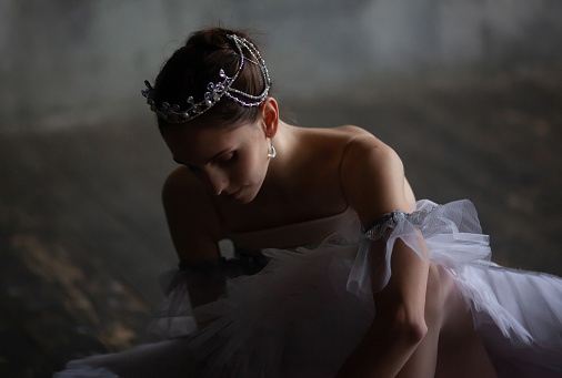 Young ballerina puts on pointe shoes.