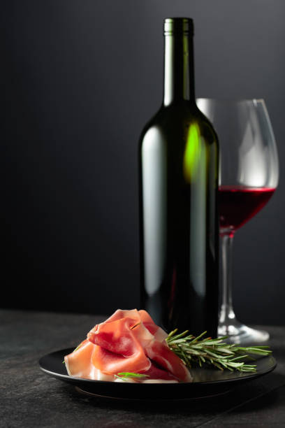 istock Prosciutto with rosemary and red wine on a black background. 1929879770