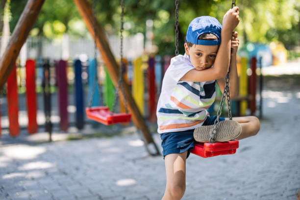 Lonely boy on a swing feeling sad