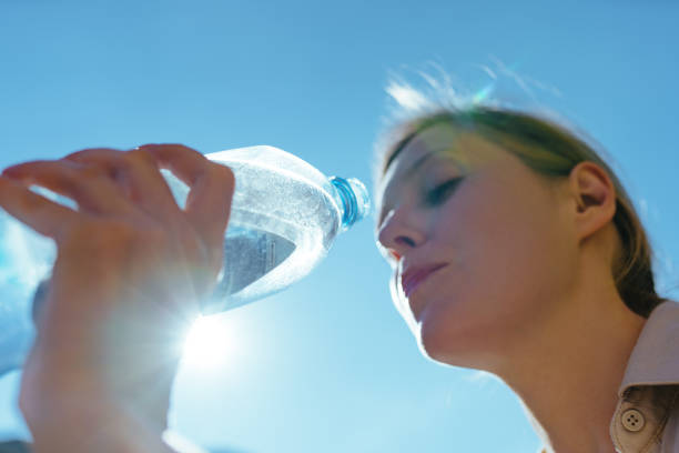 istock Young beautiful woman drinking pure water from a bottle on blue 1929886257