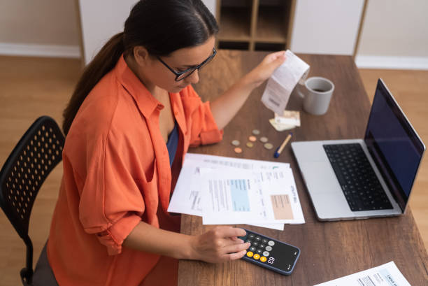 istock top view woman, with laptop tracks household expenses using her smartphone calculator. 1929887614