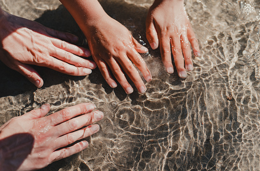 Mother and child's washing hands in clear mountain river water