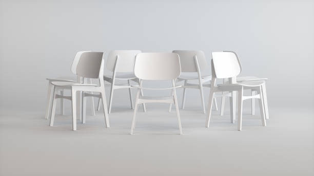 istock Seven White Chairs Arranged in a Circle Facing Out on a Gray Studio Background. Business concept. 1929888555
