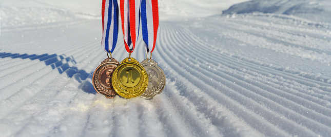 real Gold, silver and bronze medals hanging on red ribbons isolated lying on prepared, new snow ski slope