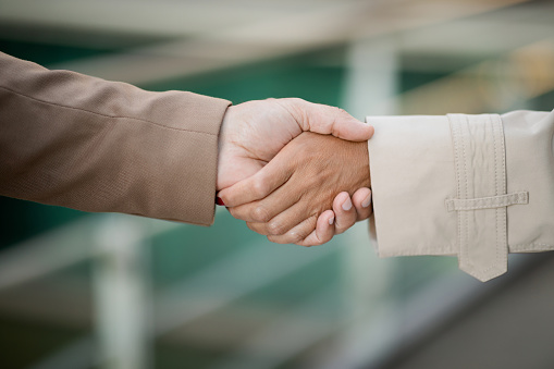 Closeup hands of man and woman shaking hands. Unrecognizable business partners or colleagues have handshake, cropped, selective focus. Business deal, teamwork concept