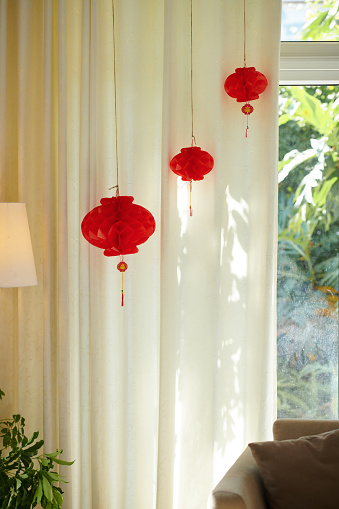 Red paper lanterns hanging in room decorated for Tet party