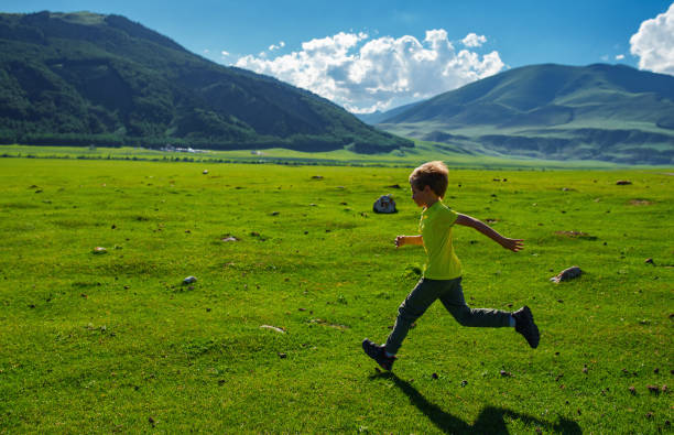 istock Boy running fast on a green meadow in the mountains 1929889707