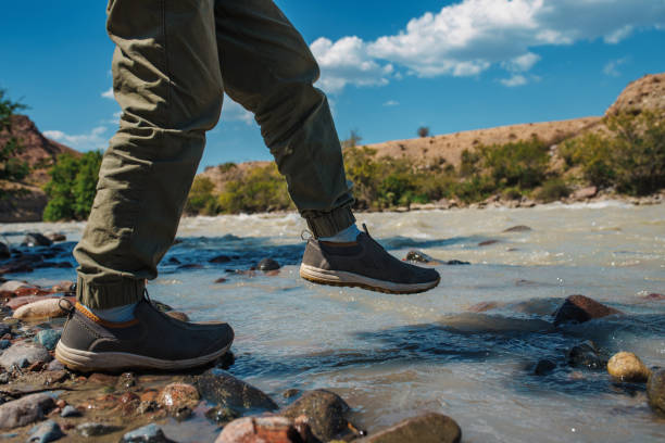 Boy walking on stones in the mountain river stock photo