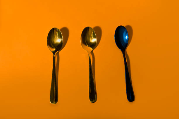 Three decorative metallic spoons on orange background
