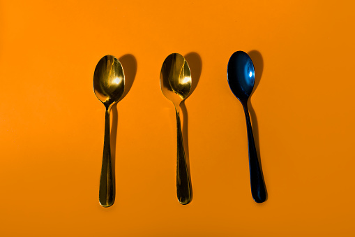 Three decorative metallic spoons on orange background