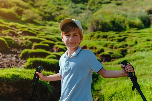 Boy hiker with trekking poles portrait in the mountains