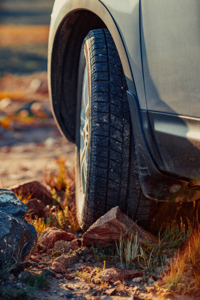 istock Car wheel standing offroad on stone close-up view 1929912827