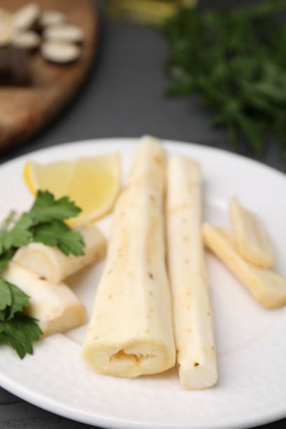 istock Cut raw salsify roots with parsley and lemon on white plate, closeup 1929917715