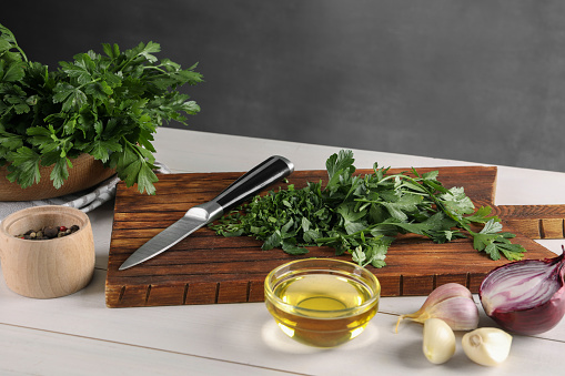 Fresh green parsley and different products on white wooden table