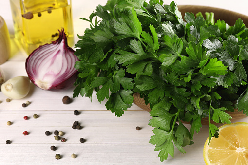 Fresh green parsley, spices and other products on white wooden table