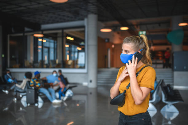 istock Caucasian Female Wearing A Protective Face Mask And Using Smartphone At The Airport 1929951009