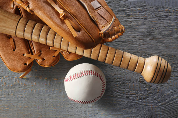 istock Baseball glove, bat and ball on grey wooden table, closeup 1929954362