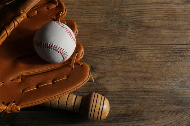 istock Baseball glove, bat and ball on wooden table, closeup. Space for text 1929954366