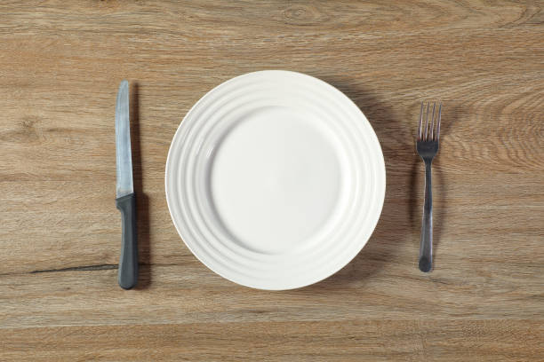 istock One empty ceramic plate with fork and knife on wooden table 1929964148