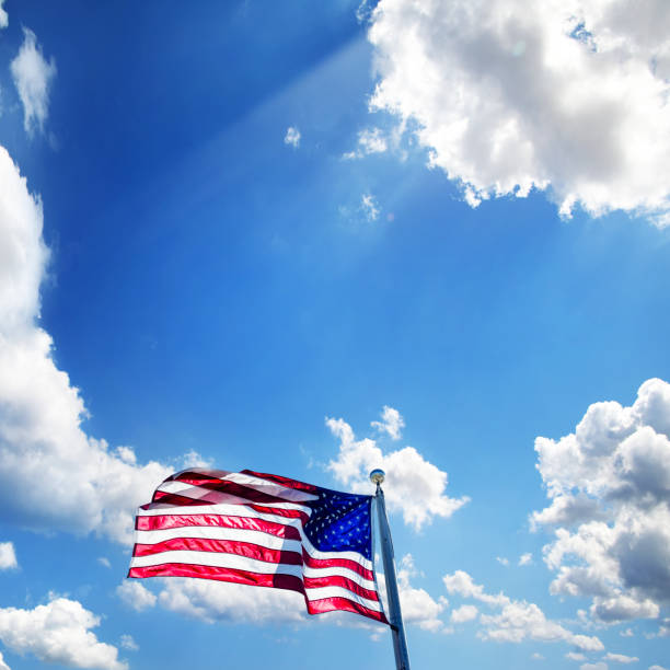 istock American flag at flagpole over dramatic sunny blue sky 1929968407