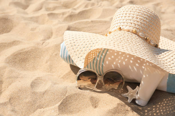 istock Straw hat, towel, sunscreen, starfish and sunglasses on sand. Space for text 1929970344