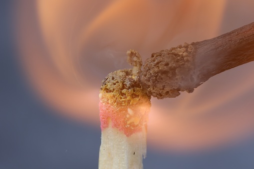 Lighting up matchstick on grey background, macro view