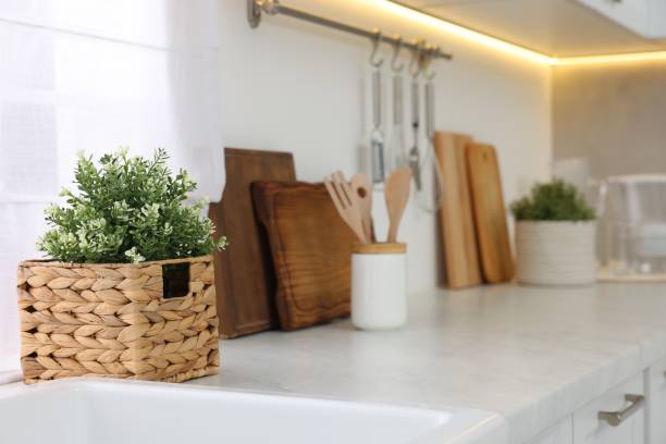 istock Beautiful potted artificial plant on countertop in kitchen, space for text. Home decor 1929975954
