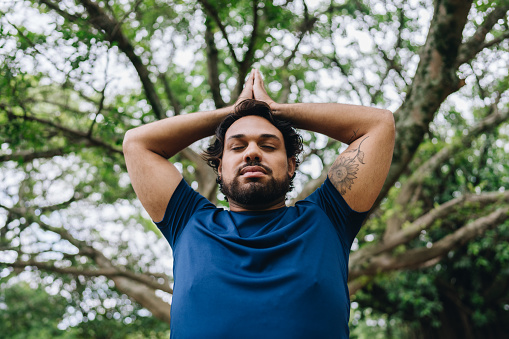 Mid adult man doing yoga at public park