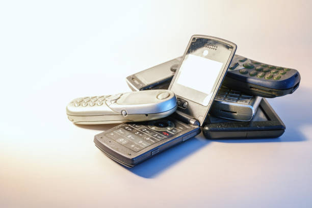 Dirty outdated cell phones in a small pile on a light background, short-lived electronic waste, consumption of valuable resources and laborious disposal, copy space, selected focus, narrow depth of field
