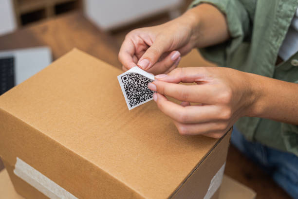 istock woman hands affix QR code sticker to package, e-commerce delivery and online shopping 1930001169
