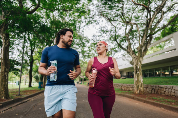 istock Couple talking and jogging at public park 1930006450
