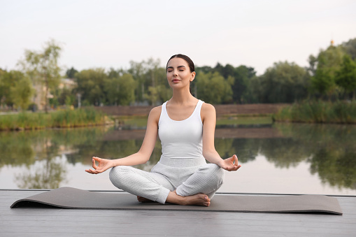 concentrated girl in lotus position doing yoga on the nature