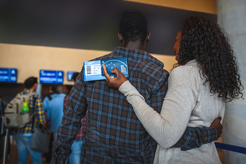 People waiting for a check in at the airport. Holding luggage and boarding passes.