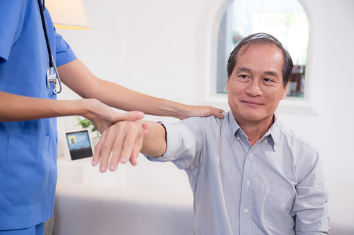 Caregiver doctor or nurse training stretching hand and arm with patient senior man for physical therapy and rehabilitation, physiotherapist assistance elderly exercising, medical and insurance.