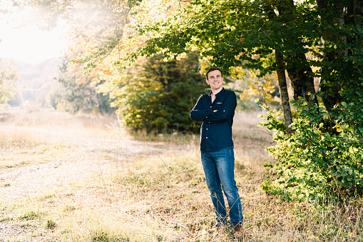 Portrait of a young handsome man in beanie and sweater in the woods.