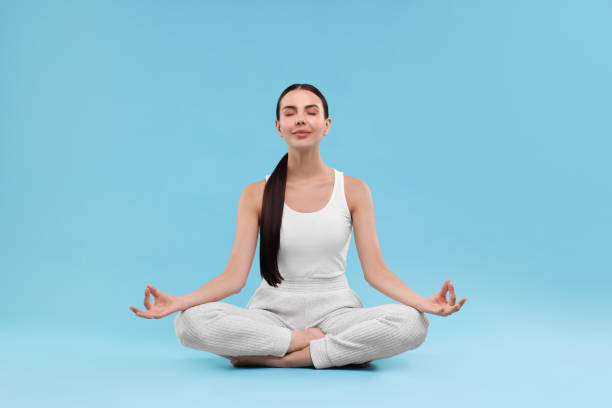 istock Beautiful young woman practicing yoga on light blue background. Lotus pose 1930047998
