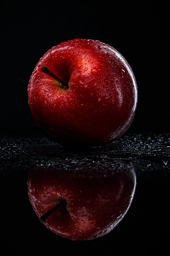 Fresh organic red apples in a bowl on a black background, close up