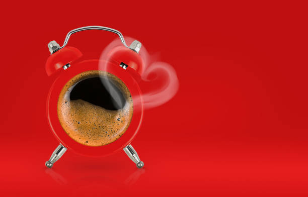 Alarm clock with coffee and steam in the heart shape on red background, copy space. Loving coffee or Valentine's day celebration concept