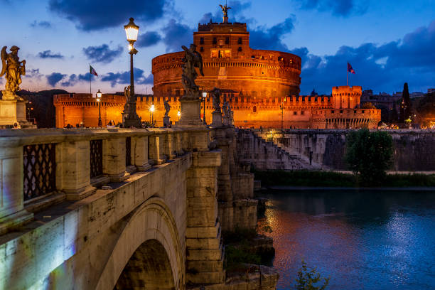 Night view of Castel Sant’Angelo in Rome, beautifully illuminated and surrounded by evening visitors