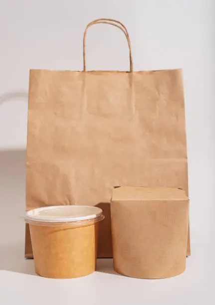 Photo of Paper package for food delivery. Beige bag, wok box and Asian soup cup