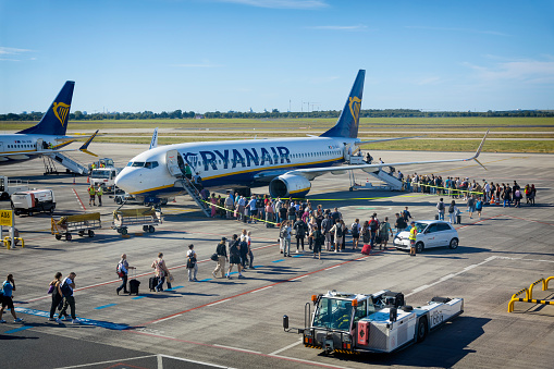 Passengers boarding a Ryanair flight via stairs leading to the front and rear doors of the aircraft in Berlin Brandenburg, Germany