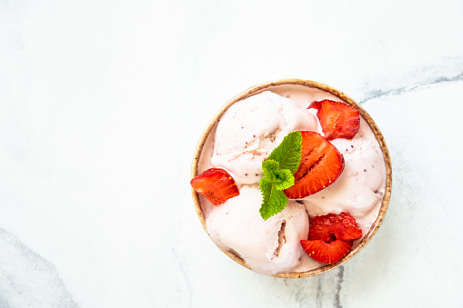 Homemade ice cream with fresh strawberries on white table. Top view with copy space.