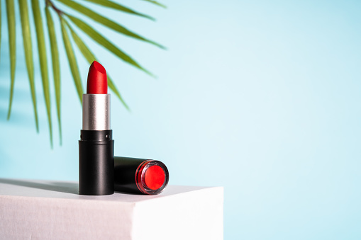 Lipstick on podium at blue background. Makeup, cosmetic product.