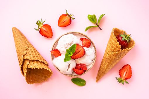 Homemade ice cream with fresh strawberries on pink background. Flat lay.