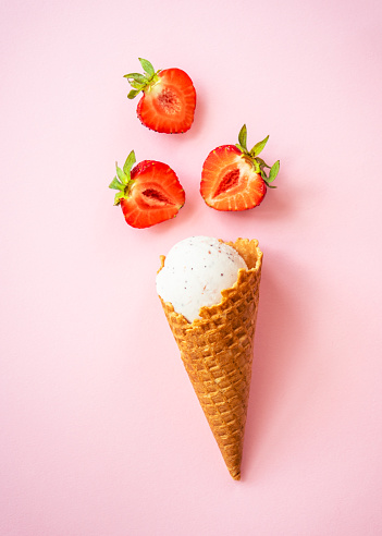Strawberry ice cream. Ice cream cone top view on pink.