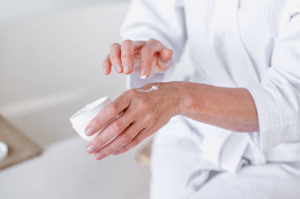 istock Mid aged woman applying moisturizer cream on hands 1930214016