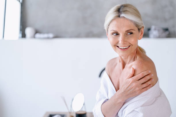 istock Smiling senior woman in bathrobe touching her naked shoulder 1930214021