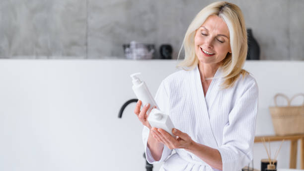 Mature woman wearing bathrobe choosing product for morning routine
