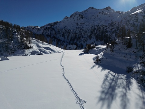 Snowy winter landscape with snowcapped trees in front and a valley and mountains in the background. Photographed in Brandnertal, Vorarlberg, Austria.