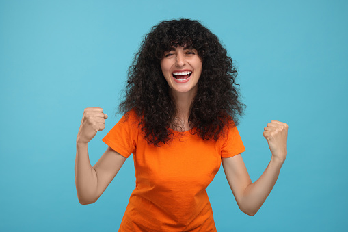 Happy sports fan celebrating on light blue background